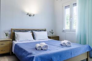 a bedroom with a blue bed with towels on it at The Green Yard Apartment in Skopelos Town