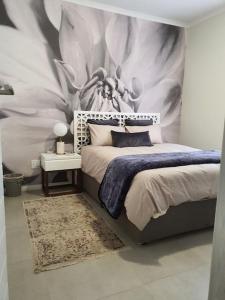 um quarto com uma cama com um quadro na parede em City Slick at 92 on Stylish Apartment in Carlswald em Midrand