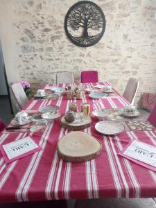 une table avec des nappes et un tissu de table rose et blanc dans l'établissement L' ART CHAMP BEAU, 