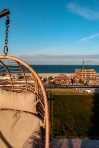 einen Rattansessel auf einem Balkon mit Blick auf den Strand in der Unterkunft Aqua Vista NUBA - Vedere Top la Mare si Lac - Summerland in Mamaia