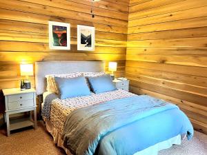 um quarto com paredes de madeira e uma cama com almofadas azuis em Beautiful Cabin on 83 Acres near New River Gorge National Park em Hico