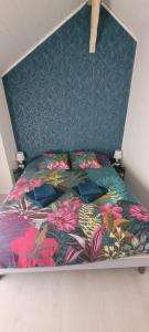 a bed with a floral comforter in a bedroom at la maison de l'abeille de Percey in Percey-le-Pautel