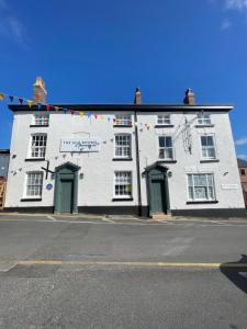 a white building with green doors on a street at The Silk Rooms, at The Freemasons Inn in Knutsford