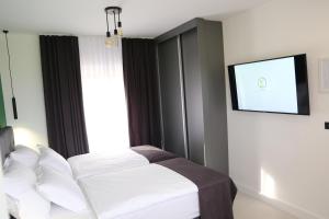 a bedroom with a bed with white sheets and a window at Flora Studio Apartments in Korenica