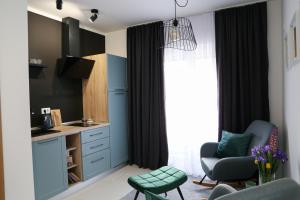 a small kitchen with blue cabinets and a chair at Flora Studio Apartments in Korenica
