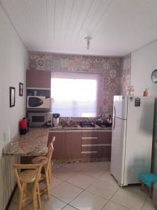 cocina con nevera, mesa y sillas en Casa Em Penha Sc, en Penha