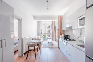 Homie Suites - Newly-constructed Apartment Complex in Beşiktaş في إسطنبول: مطبخ مع دواليب بيضاء وطاولة وكراسي