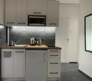 a kitchen with white cabinets and a microwave at Mieszkanie na Ogrodach in Bydgoszcz
