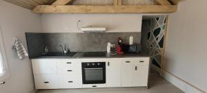 een keuken met witte kasten en een zwarte oven bij la maison de l'abeille de Percey in Percey-le-Pautel