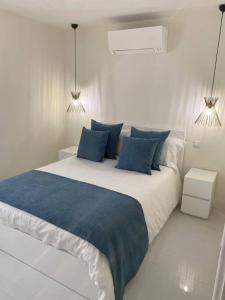 a white bedroom with a large bed with blue pillows at Cap d ail Appartement aux portes de Monaco in Saint-Antoine