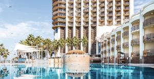 a swimming pool in front of a building at Daniel Hotel - Residence Seaside Luxury Flat in Herzliya