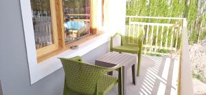 twee stoelen en een tafel op een veranda bij Chandan Guest House in Leh