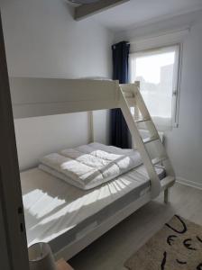 ein weißes Etagenbett in einem Zimmer mit Fenster in der Unterkunft Location saisonnière à St Hilaire de Riez in Saint-Hilaire-de-Riez