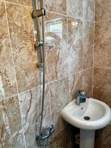 La salle de bains est pourvue d'un lavabo et d'une douche. dans l'établissement Secret Garden Guest House, à Qabala