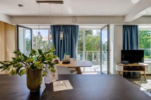 een woonkamer met een grote tafel en een eetkamer met blauwe gordijnen bij FeWo Prora - Luft und Loft in Binz
