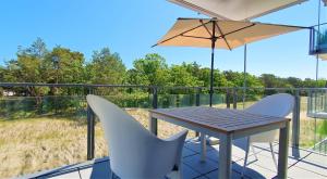 een tafel en twee stoelen en een parasol op een balkon bij FeWo Prora - Luft und Loft in Binz