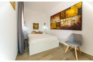 Un pequeño dormitorio con una cama y una silla. en APARTAMENTOS MAPAMUNDI, en Badajoz
