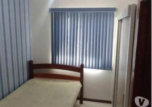 1 dormitorio con silla y ventana con cortinas en Casa Em Penha Sc, en Penha