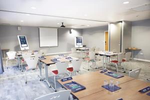 a classroom with tables and white chairs and a whiteboard at Campanile Hotel Northampton in Northampton