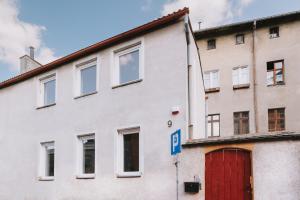 um edifício branco com uma porta vermelha e uma garagem vermelha em Między Murami em Toruń