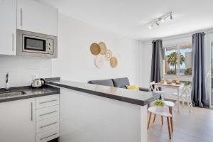 a white kitchen with a counter and a dining room at Vistamarina B201 By IVI Real Estate in Torremolinos