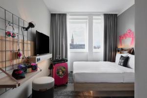 a hotel room with a bed and a large window at Moxy Duesseldorf City in Düsseldorf