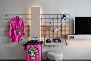 a room with a pink suitcase and a tv at Moxy Duesseldorf City in Düsseldorf