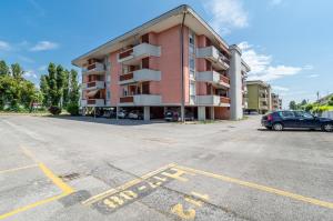 un parking en face d'un bâtiment rose dans l'établissement Domus Lucis Apartment Terrace & Private Parking, à Marinella di Sarzana