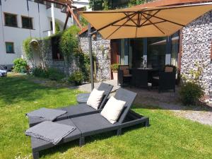 een patio met een parasol, stoelen en een tafel bij Gurgltal Refugia in Tarrenz