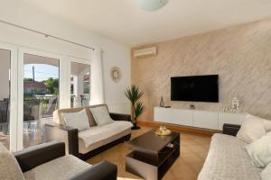 uma sala de estar com 2 sofás e uma televisão de ecrã plano em House Leonardo em Galovac
