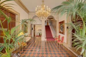 a hallway with a chandelier and a staircase with plants at Palácio das Especiarias in Lisbon
