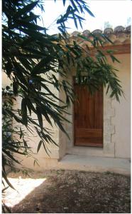 a wooden door of a house with a tree in front at Apartement Les Alpilles in Eygalières