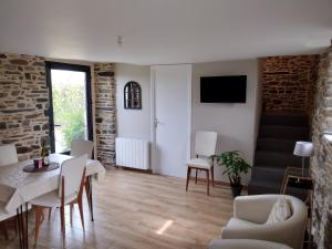 sala de estar con mesa, sillas y TV en Gîte charmant typique Breton Ti Quartier en Pordic