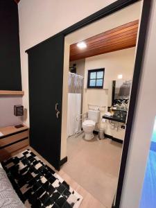 La salle de bains est pourvue de toilettes et d'une porte noire. dans l'établissement Pousada Terrazzo Bonjardim, à Campos do Jordão