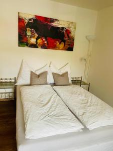 ein weißes Bett in einem Schlafzimmer mit einem Gemälde an der Wand in der Unterkunft Appartement Kirchleiten in Henndorf am Wallersee