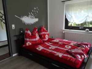 een slaapkamer met een bed met rode lakens en kussens bij 1 Raum-Ferienwohnung am Rosenberg in Goslar