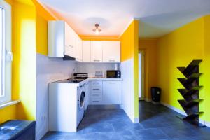 a kitchen with yellow walls and a washer and dryer at Da Aurora al 27 in Manciano