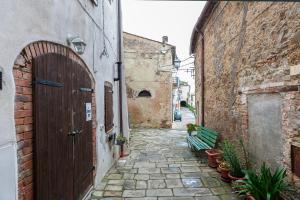 an alley with a wooden door and a green bench at Da Aurora al 27 in Manciano