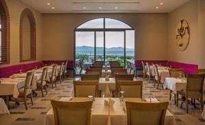 een eetkamer met tafels en stoelen en een groot raam bij My Ella Bodrum Resort & Spa in Mugla