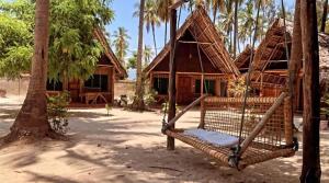 a hammock in front of a house with palm trees at Your Zanzibar Place in Paje