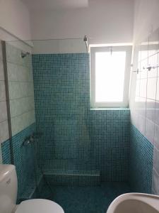 bagno con doccia piastrellata verde e finestra di Cathrin Beach Apartments a Stavros