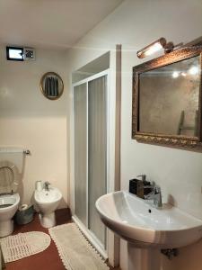 een badkamer met een wastafel, een toilet en een spiegel bij La tua casa nel Chianti in San Donato in Poggio
