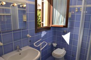 niebieska kafelkowa łazienka z toaletą i umywalką w obiekcie Le Villette al Centro w mieście San Teodoro