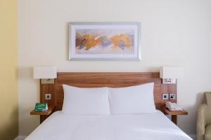 - une chambre avec un lit blanc et une chaise dans l'établissement Holiday Inn Rochester-Chatham, an IHG Hotel, à Chatham