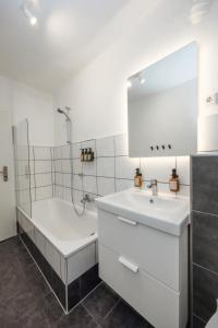 ein Badezimmer mit einer Badewanne, einem Waschbecken und einem Spiegel in der Unterkunft 80qm Luxuriöse Designerwohnung im Herzen Bochums in Bochum