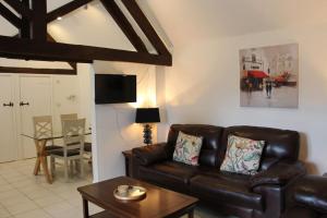 a living room with a leather couch and a table at Peaceful and tranquil 2 bedroom Deer Cottage in Chippenham