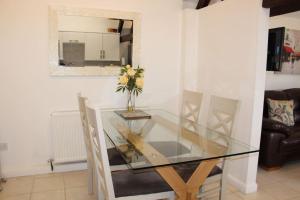 a glass dining room table with a vase of flowers on it at Peaceful and tranquil 2 bedroom Deer Cottage in Chippenham