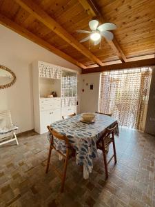 ein Esszimmer mit einem Tisch und einem Deckenventilator in der Unterkunft Appartamento - Rosamarina in Torre Colimena