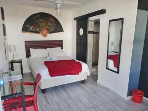 een slaapkamer met een bed met een rode deken en een spiegel bij Melville House in Johannesburg