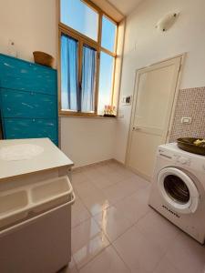 eine Küche mit einer Waschmaschine und einem Fenster in der Unterkunft Appartamento - Rosamarina in Torre Colimena